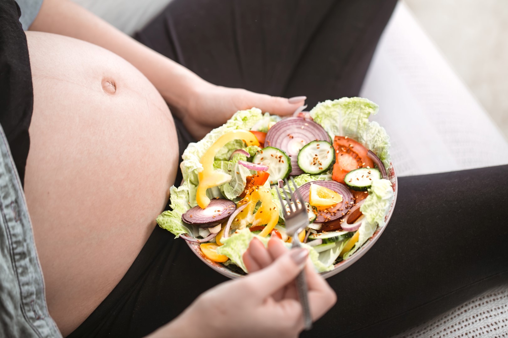 Young pregnant woman eating vegetable salad